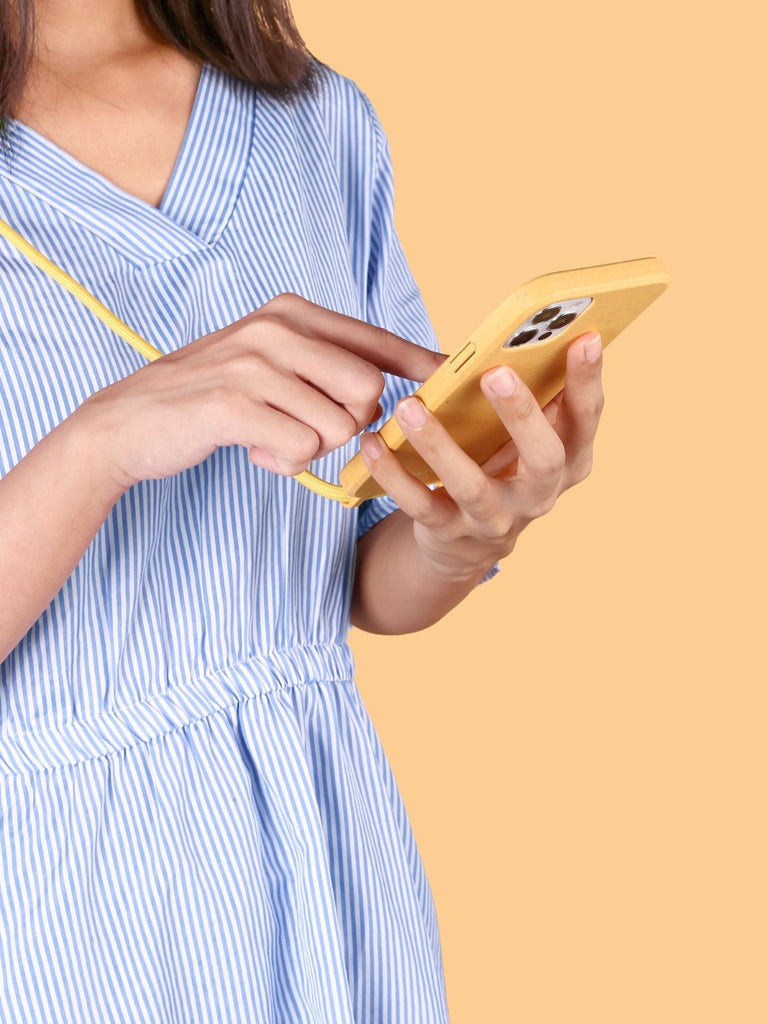 A woman is using an iPhone with a yellow phone case
